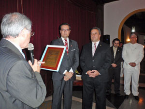 Antonio Alamo lee la placa que la directiva del Hermandad Canaria entregó como reconocimiento a  Moisés Morera Martín, segundo por la izquierda.