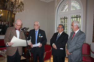 El embajador español Carlos Robles lee el diploma que acompaña a la Medalla de Honor de la Emigración que se le entregó a José Antoni Fanjul, a su izquierda.