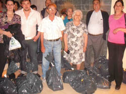 Los beneficiarios de las ayudas junto a las bolsas con alimentos.