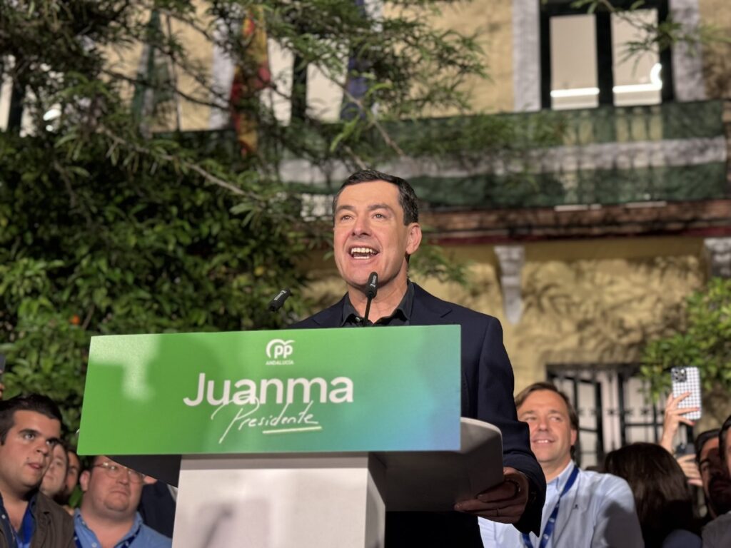 Juanma Moreno celebra la victoria con militantes y simpatizantes del PP frente a la sede del partido en Sevilla.