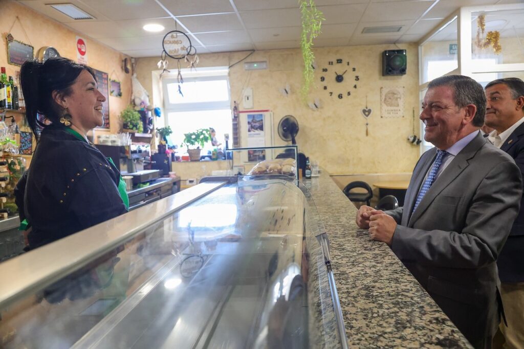 El consejero de la Presidencia, Luis Miguel González Gago, con la dependienta del bar La Casuca de Yoa, en el municipio de Niharra (Ávila).